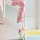 Centro floral con número de helio y base orgánica de globos para decoración de cumpleaños